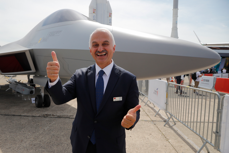 Turkish Aerospace CEO Temel Kotil makes the thumbs up sign as he poses next to a mock-up of a TF-X fighter jet displayed at Paris Air Show, in Le Bourget, east of Paris, France, Tuesday, June 18, 2019.